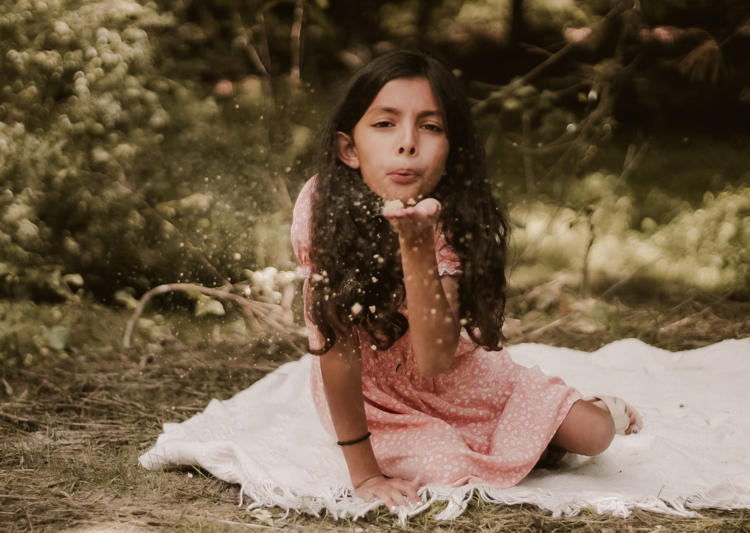 Child blowing glitter in a woodland setting