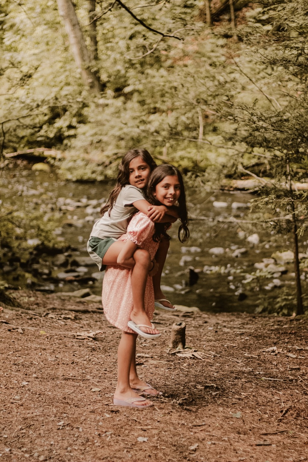 Two children together beside a woodland stream