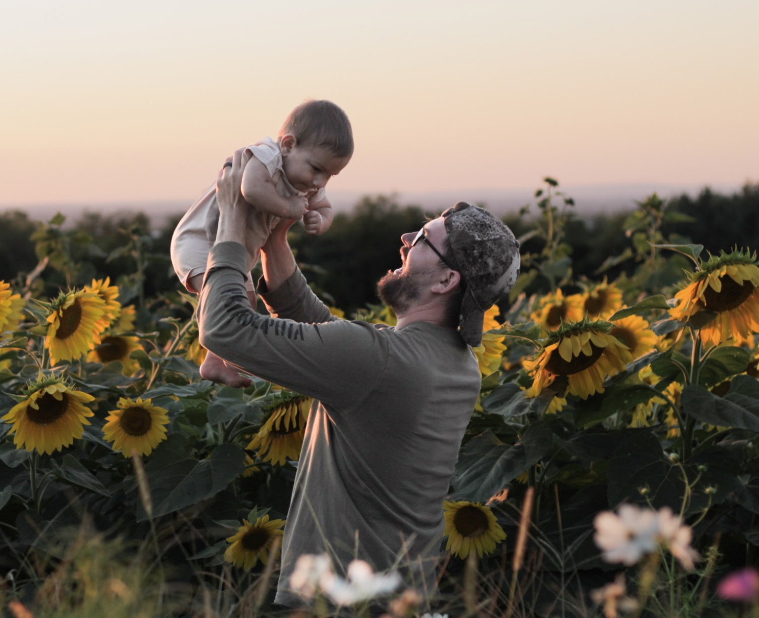 Father lifting his baby in a sunflower field